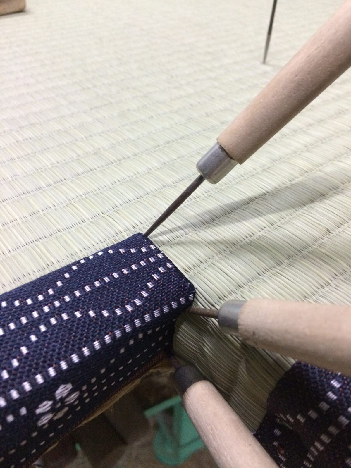 柱の出っ張りに合わせた畳の切欠け部分を手縫いしている作業